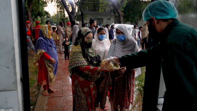 Un trabajador de Saylani Welfare Trust da comida a las mujeres en Islamabad, Pakistán. (Foto AP / Anjum Naveed)