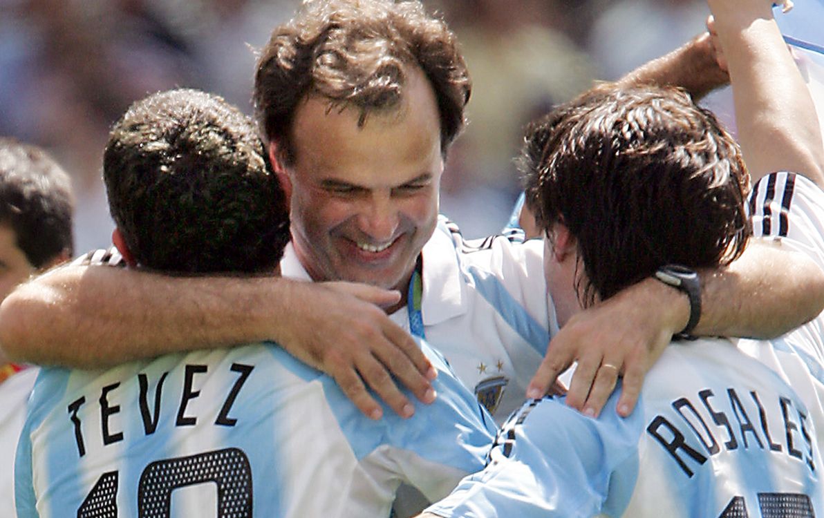 Argentines national football team Carlos Tevez (L) and Mauro Rosales (R) celebrate with their coach Marcelo Bielsa after their team defeated Paraguay at the Olympic Stadium in Athens 28 August 2004 during the Olympic mens football final Paraguays vs Argentine of the 2004 Olympic Games.  Argentina won the Olympic Games football gold medal here on Saturday with a 1-0 victory against Paraguay. AFP PHOTO ANTONIO SCORZA (Photo by ANTONIO SCORZA / AFP)