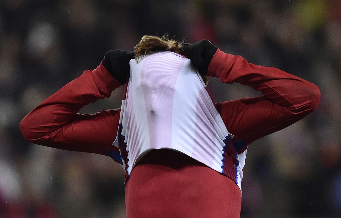 Atletico Madrids French forward Antoine Griezmann covers his face with his jersey as he reacts after missing a goal opportunity during the Spanish league football match Club Atletico de Madrid vs RCD Espanyol at the Vicente Calderon stadium in Madrid on December 3, 2016. (Photo by GERARD JULIEN / AFP)
