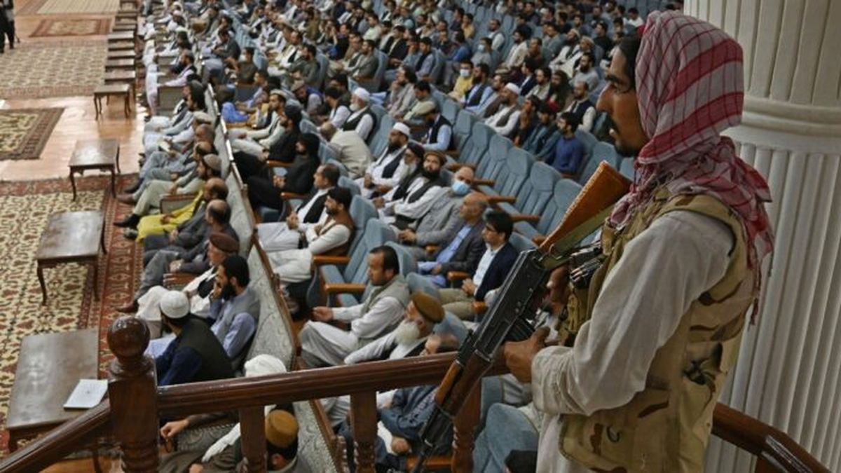 Un combatiente talibán hace guardia mientras habla el ministro de Educación Superior interino