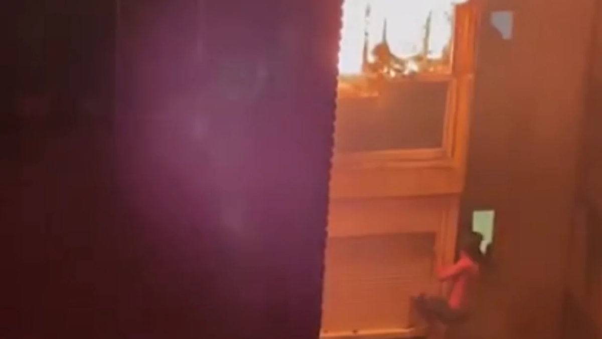 El joven escapando del fuego colgado del edificio. (Foto: capturavideo)