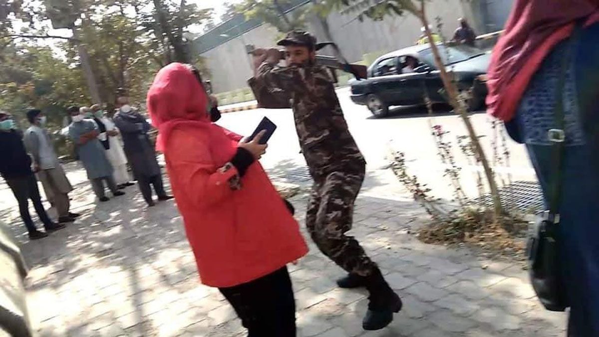 Un policía está a punto de golpear con su fusil a una mujer por las calles de Kabul