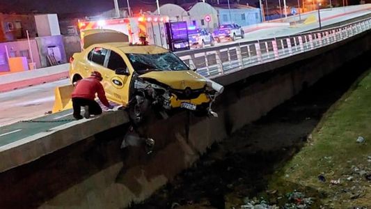 Video: en un impresionante choque, un taxi impactó contra una moto y quedó colgado de un puente
