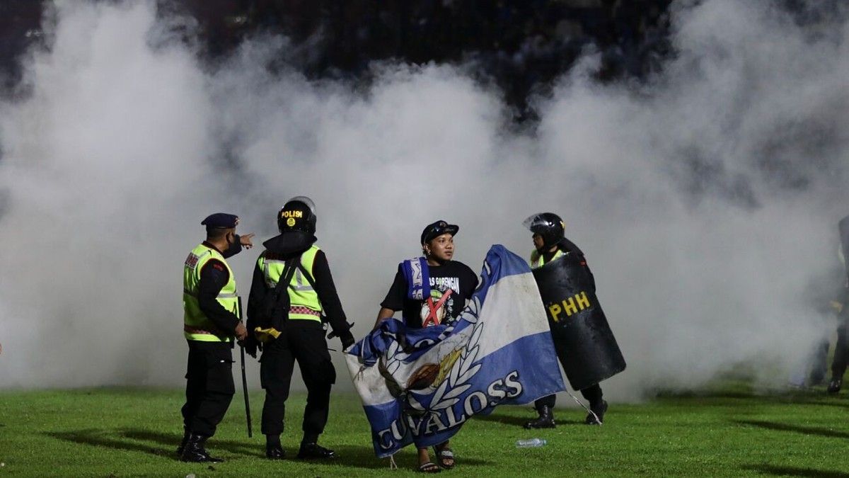Un hincha ingresa al campo mientras los policías hacen guardia durante la violencia que se desató en el estadio Kanjuruhan de Indonesia. (Foto: EFE) 