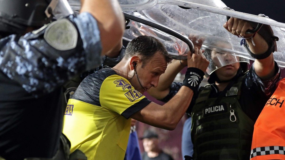 El árbitro Darío Herrera sale de la cancha custodiado por policías al finalizar el partido entre Lanús y River. (Foto: AFP)&nbsp;
