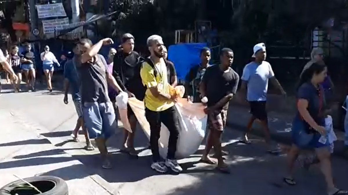 Vecinos de la favela Alemao llevan a los muerto envueltos en una sábana (Foto: AP)
