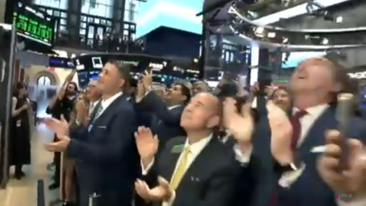 Los brokers del recinto del Wall Street, celular en mano para las fotos, y aplaudiendo a Milei. (foto: Captura de TV)