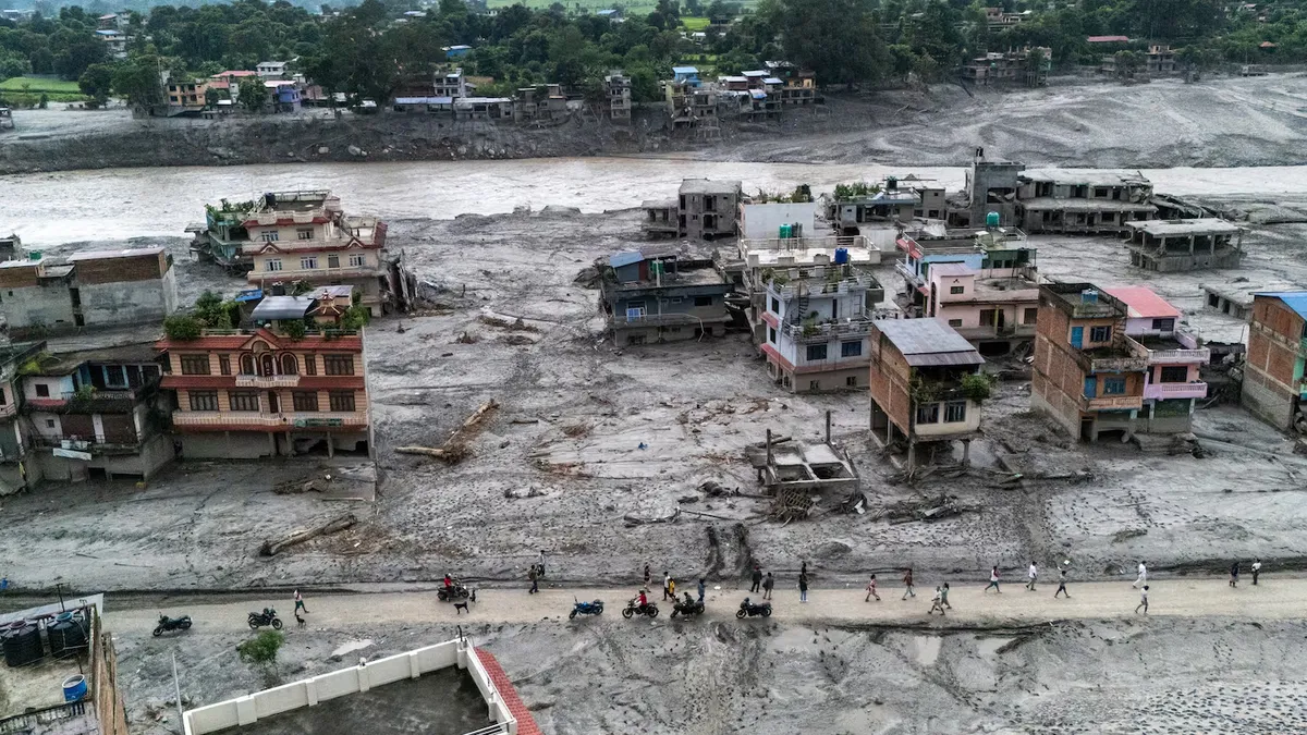 Vista a&eacute;rea de personas caminando por una ruta rodeada de casas cubiertas de barro tras las inundaciones y deslizamientos de tierra en Devighat, distrito de Nuwakot, Nepal. (Foto: REUTERS)