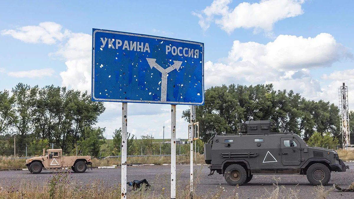 Vehículos militares a ambos lados de un cartel que marca los caminos hacia Rusia o Ucrania. La señal está llena de impactos de proyectiles luego de tres años en guerra. (Foto: Gentileza The Economist)