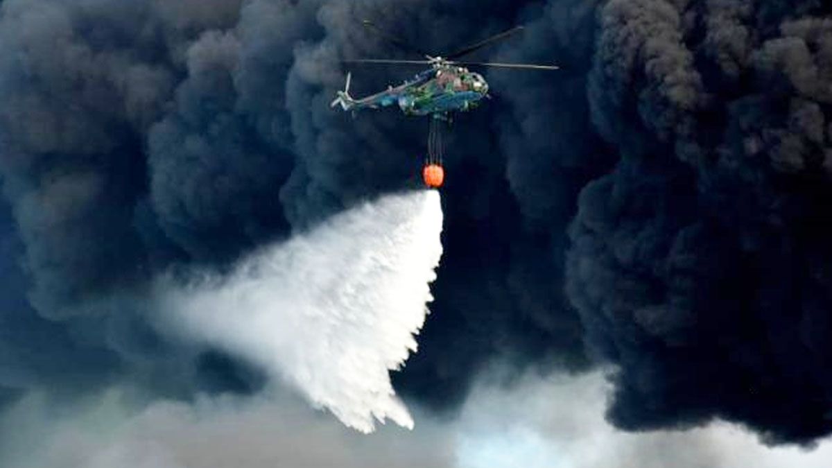 Los helicópteros hidrantes avanzan y retroceden sobre el centro del fuego,  para evitar que avance hacia otros depósitos (Foto: Granma)