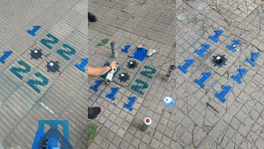 Un artista pinta bombas del Buscaminas sobre las baldosas flojas de las veredas de La Plata