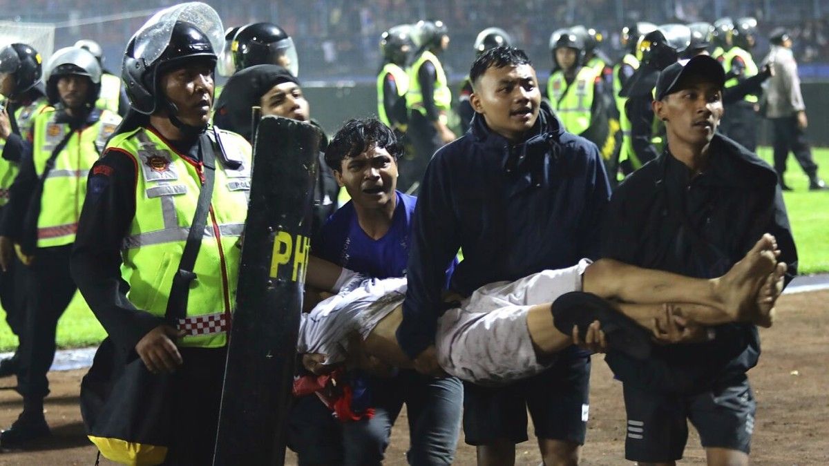 Fanáticos llevan a un hombre herido tras los enfrentamientos en el estadio Kanjuruhan en Indonesia. (Foto: EFE) 