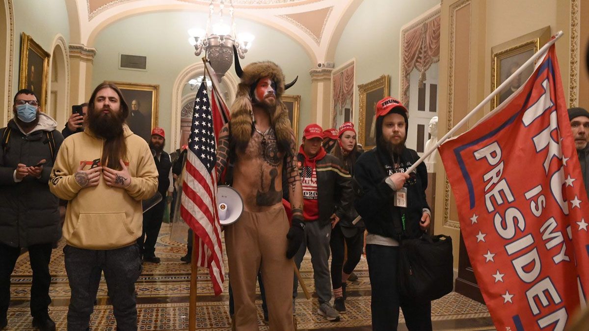 Un hombre con la bandera de confederada y una piel con cuernos en la cabeza. Símbolo de la violencia del 6 de enero de 2021 en el Capitolio norteamericano (Foto: AP)