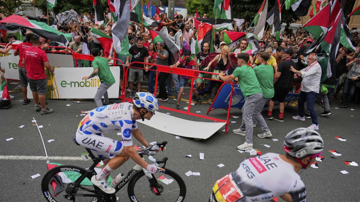 Postal para el mundo de la vuelta de España. Ciclistas corriendo ante protestas propalestinos, disturbios y choques con la policía. (foto: Reuters)