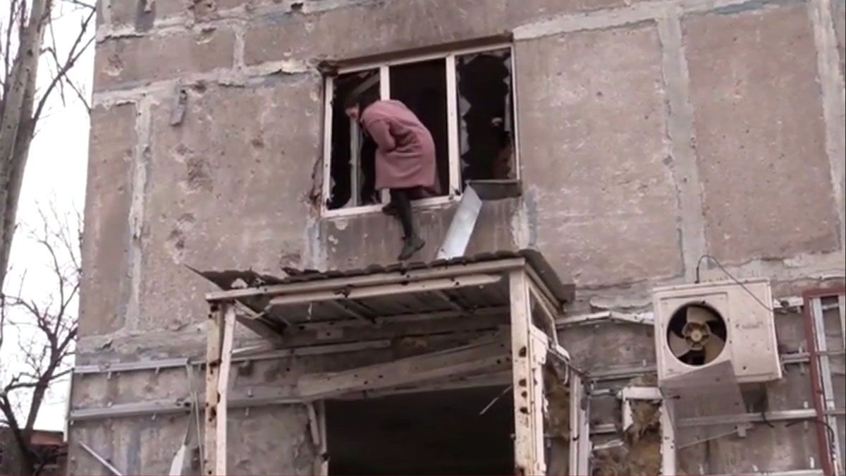 Una mujer huye por una ventana desde un edificio destruido en Mariupol (Foto: AP)