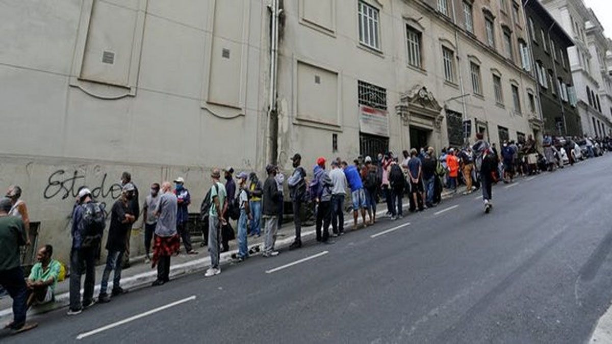 Una larga fila de gente espera a recibir alimentos en una calle del centro de São Paulo