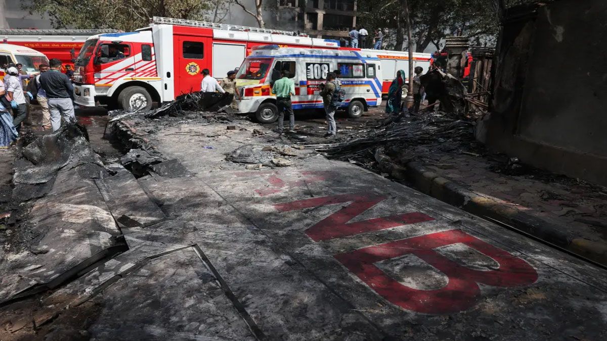 Bomberos y personas civiles caminan sobre restos de un ala del avión