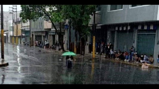 Conmovedora imagen de una mujer que soportó una intensa lluvia y evitó aglomerarse con otras personas por miedo al coronavirus