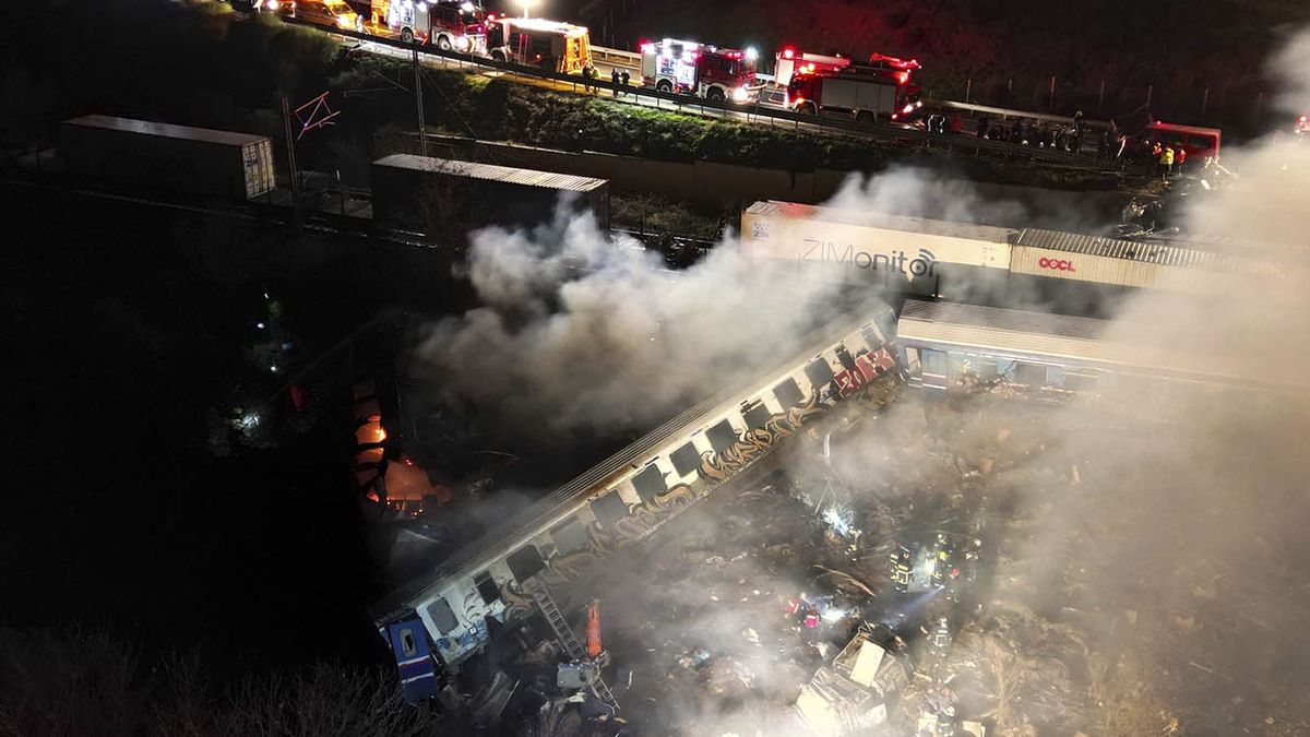 Una nube de humo emerge de vagones de tren mientras bomberos y rescatistas trabajan luego de un choque de trenes cerca de la ciudad de Larissa