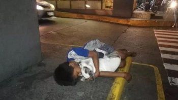 Un nene sin hogar duerme en la calle abrazado a su perro