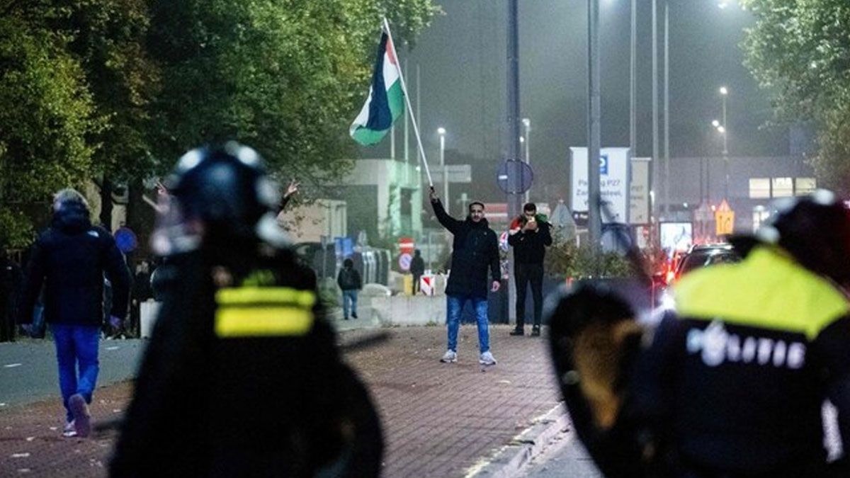 Un manifestante con la bandera palestina frente a los agentes de la policía de Ámsterdam. (foto: Gentileza arabnews)  