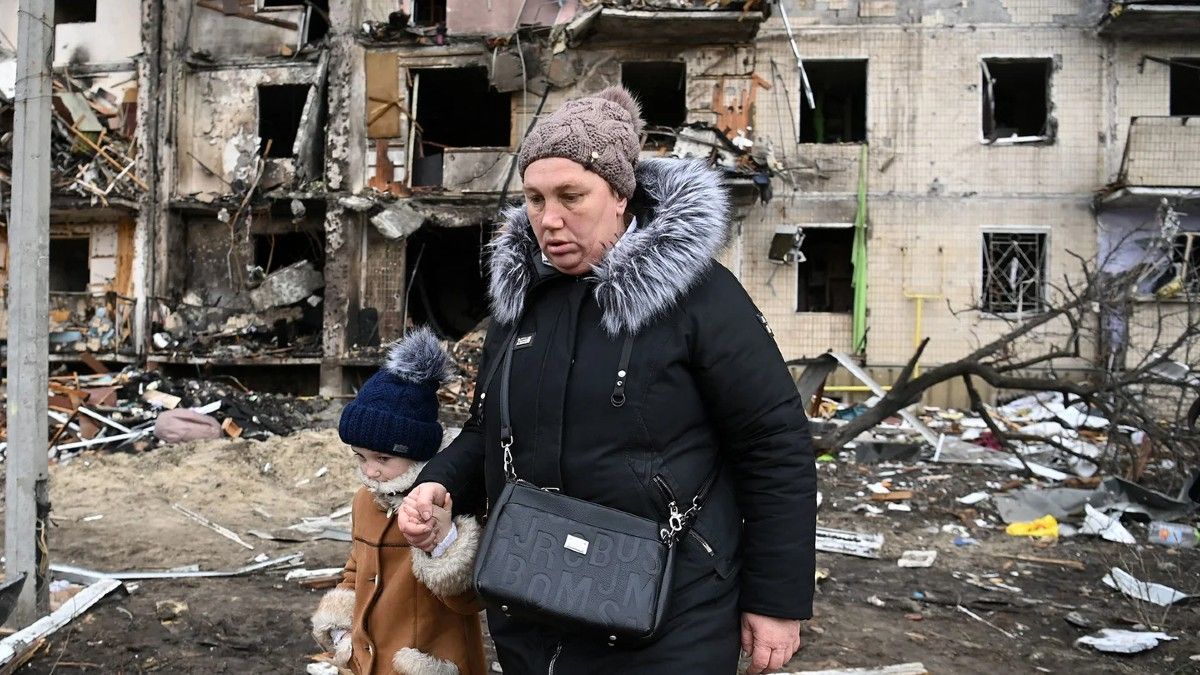 Una mujer con un niño camina frente a un edificio residencial dañado en la calle Koshytsa, un suburbio de la capital ucraniana, Kiev. 