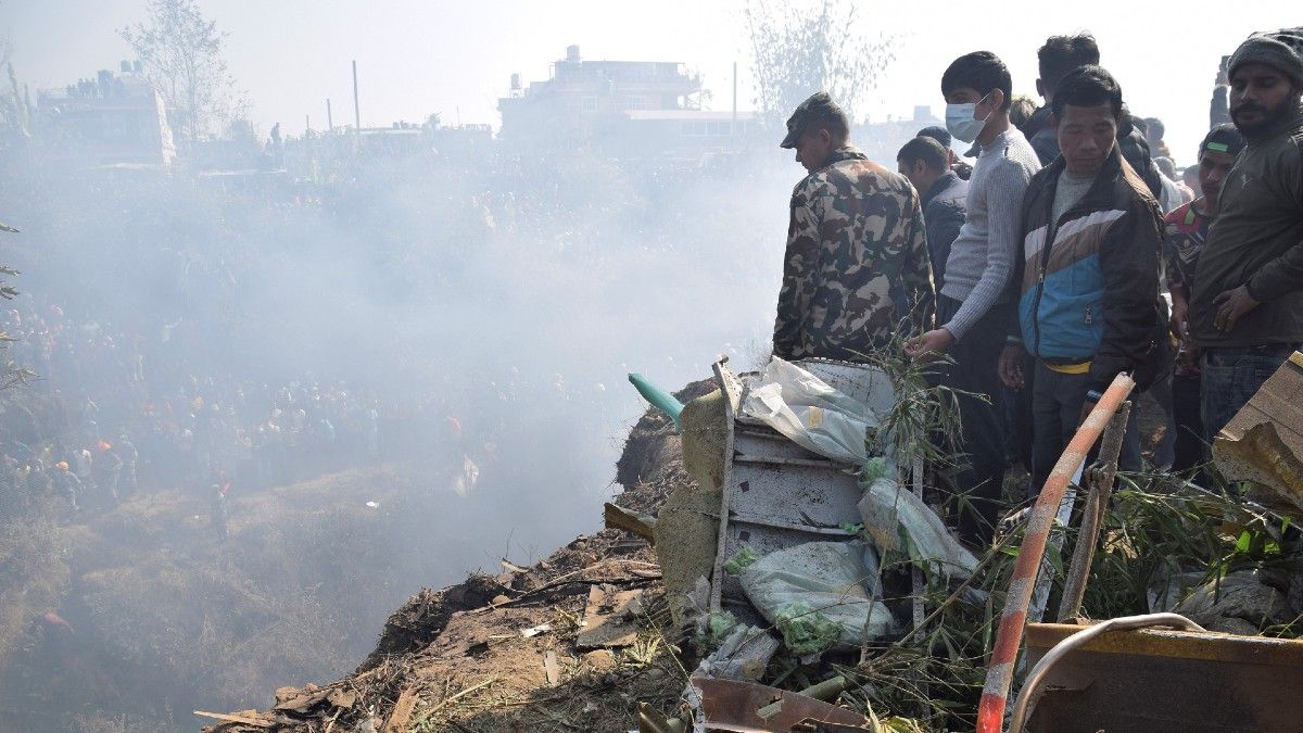 Trabajadores de rescate y civiles nepaleses se reúnen alrededor de los restos de un avión de pasajeros que se estrelló en Pokhara