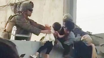 Un soldado norteamericano ya tiene en sus brazos a la niña para cruzar al por encima del muro del aeropuerto de Kabul (Foto: captura de pantalla).