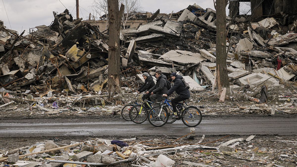 Tres hombres pasan en bicicleta junto a un edificio de apartamentos destruido, en Borodyanka, Ucrania, el 6 de abril de 2022. (AP Foto/Vadim Ghirda)