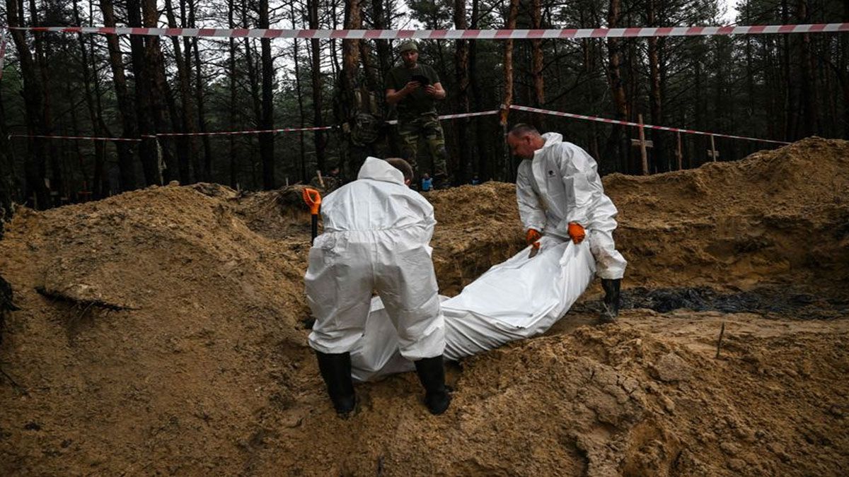 Soldados y forenses retiran los cuerpos hallados en las fosas clandestinas de Izium (Foto: Gentileza El País)