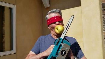 Viral: un hombre se vendó los ojos y cortó en trozos con una motosierra la manzana que sujetaba con la boca.