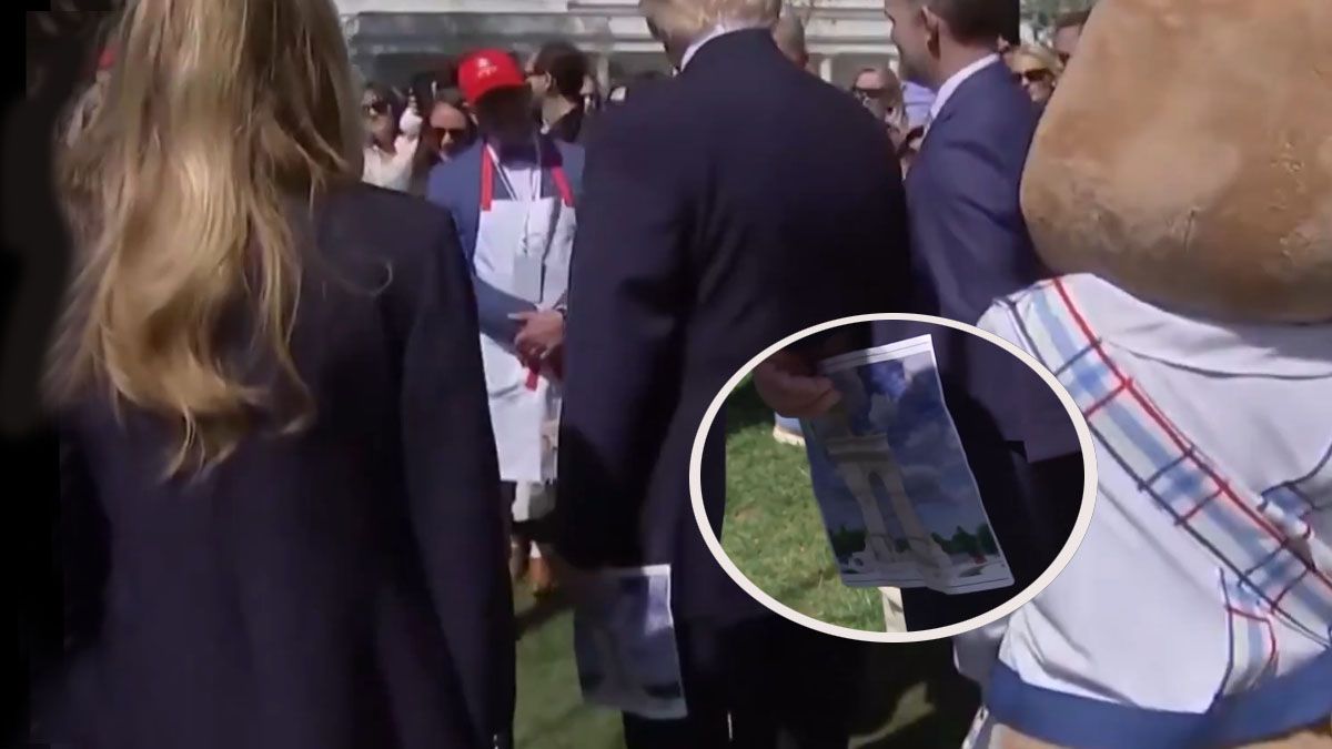 Trump en un acto con personal de la Casa Blanca. En su mano tiene una foto del proyecto del arco para Washington. (foto: A24.com)
