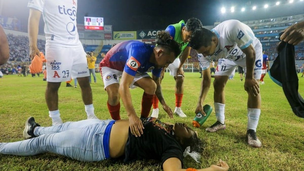 Aficionados al fútbol atienden en la cancha a los heridos por una estampida humana en el estadio Cuscatlán de San Salvador (Foto: AP)